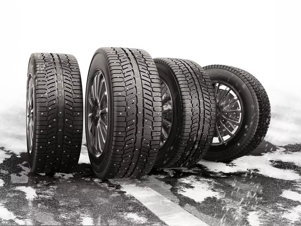 Four car tires rolling on a snow-covered road.